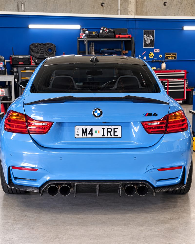 Rear view of a blue BMW M4 in the workshop