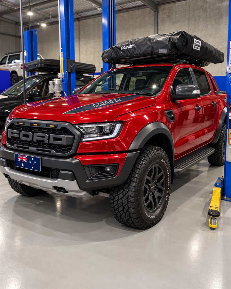 Red Ford Ranger Raptor front three-quarter view between hoists