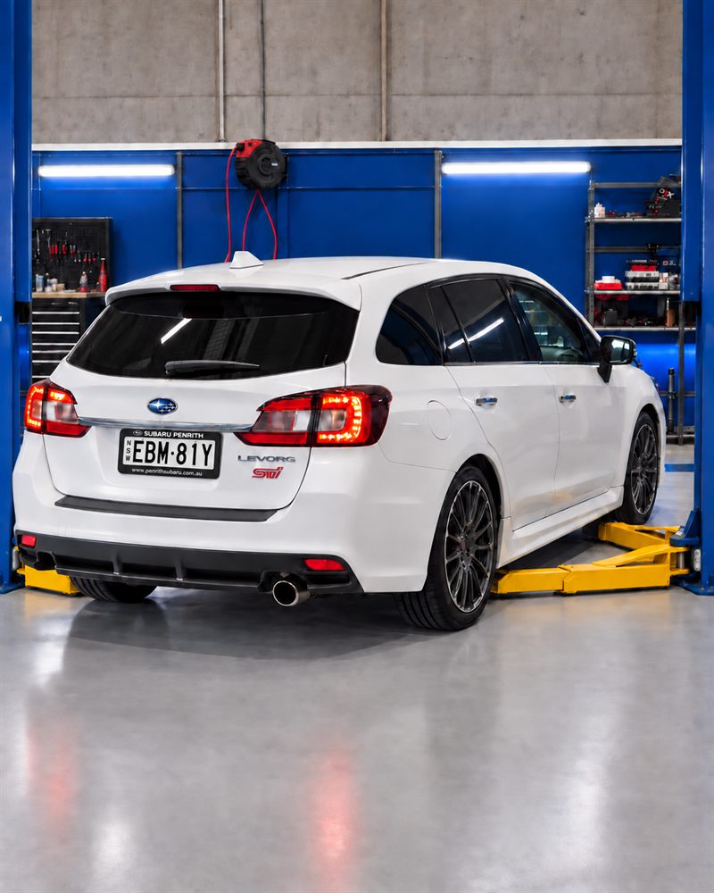 White Subaru Levorg STI raised on hoist arms