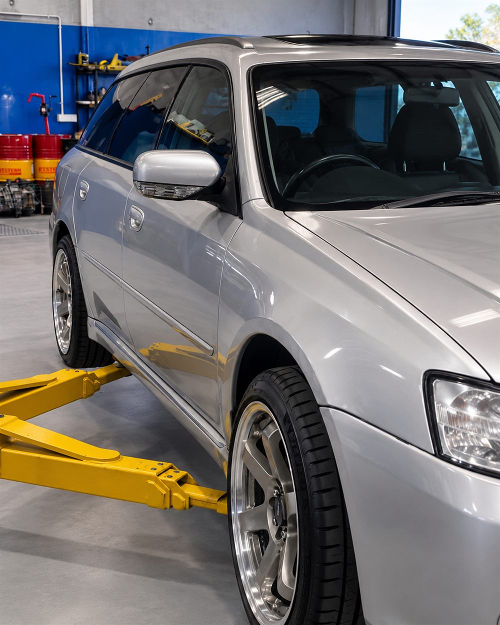 Silver Subaru Liberty wagon on hoist arms
