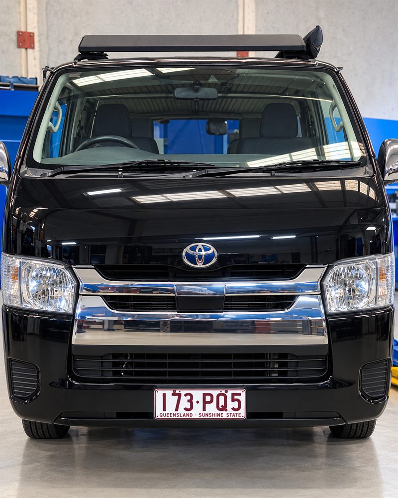 Black Toyota HiAce camper front view with roof rack