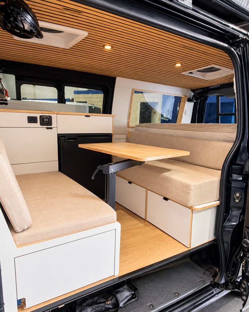 Side door open on a Toyota HiAce camper showing the dinette