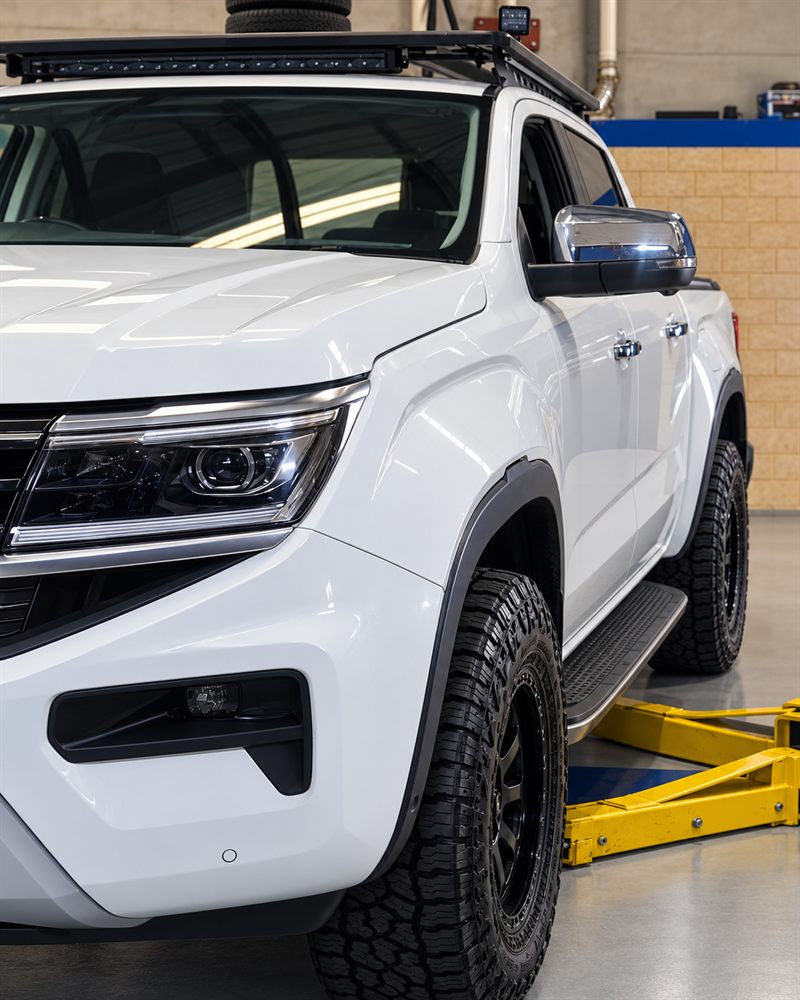 White Volkswagen Amarok V6 front three-quarter view on hoist arms