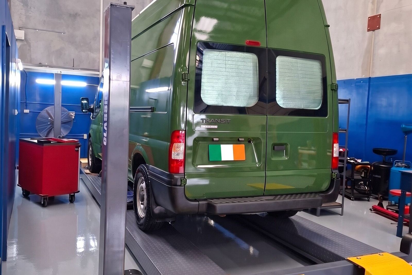 Green Mercedes-Benz Sprinter van on a hoist