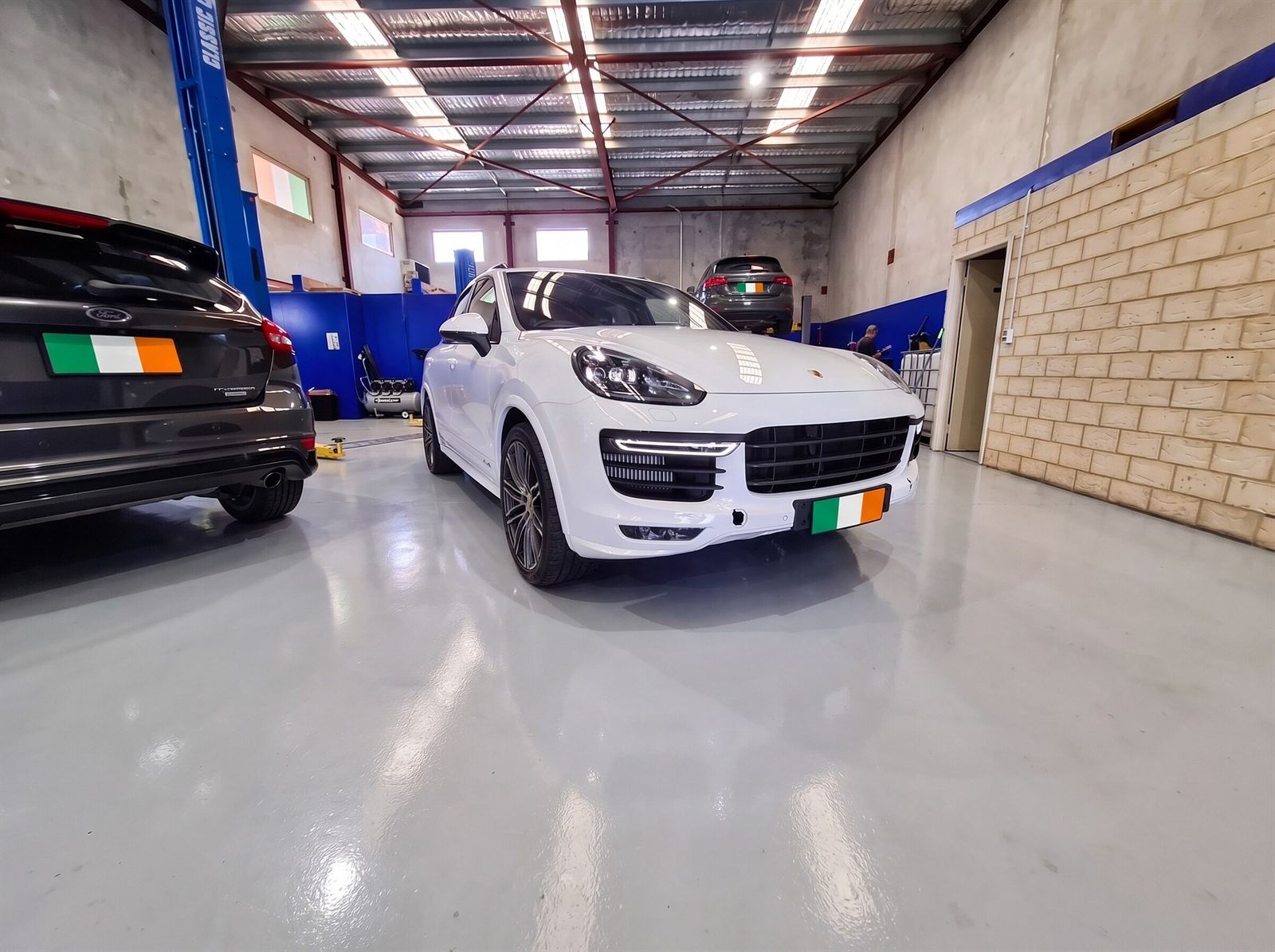 White Porsche Cayenne parked on the epoxy workshop floor