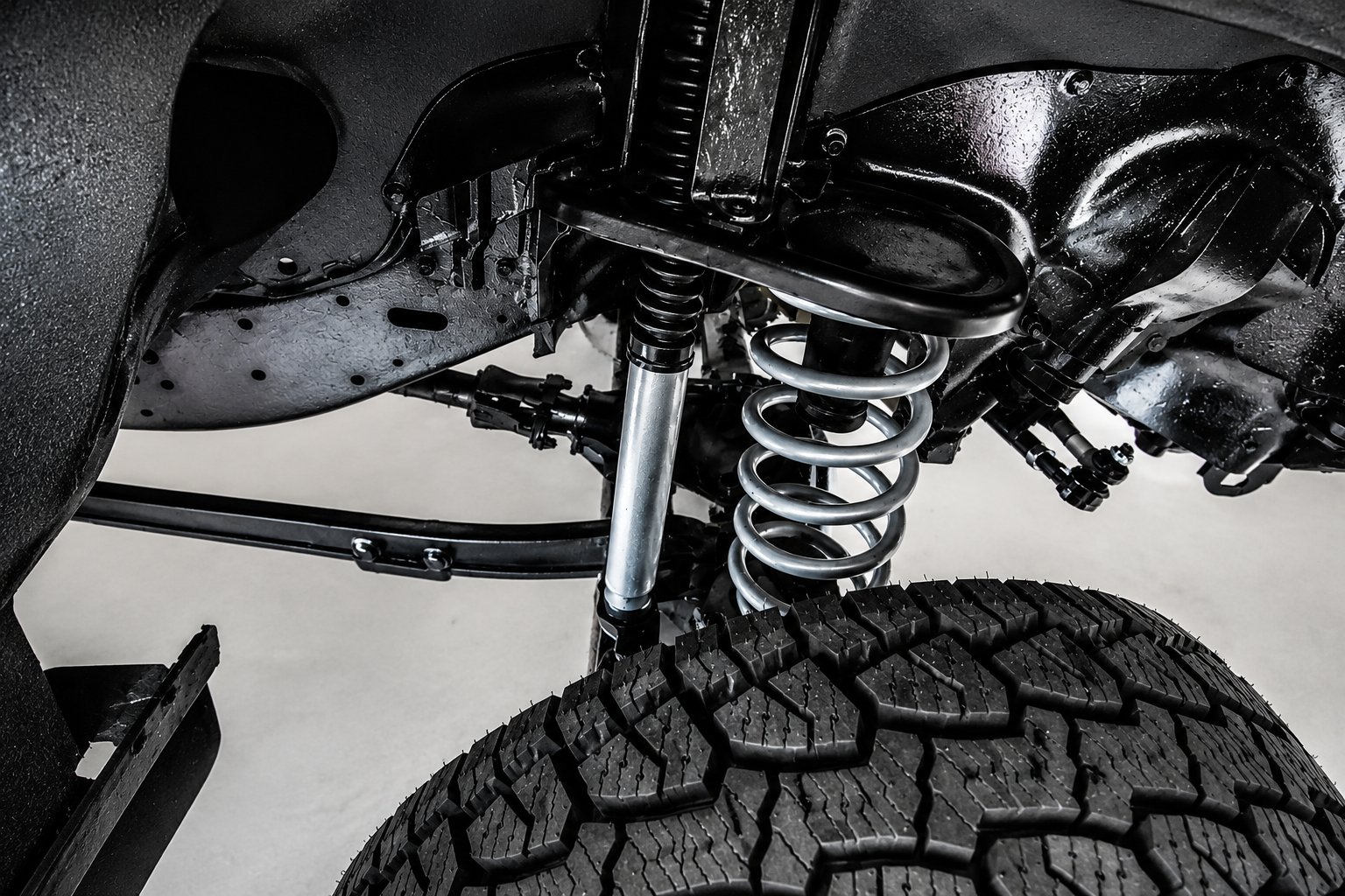 Front coil-over and upper control arm above an all-terrain tyre