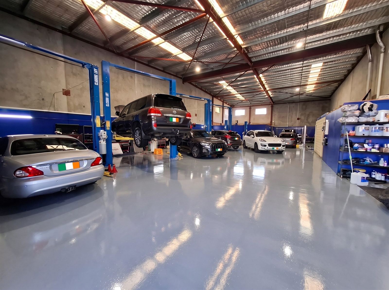 Car on a hoist mid-service with others waiting in the workshop