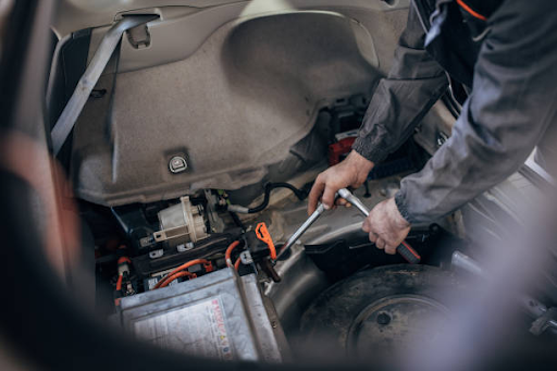 A man is engaged in battery maintenance on a car, representing Malaga’s commitment to premier car repairs.