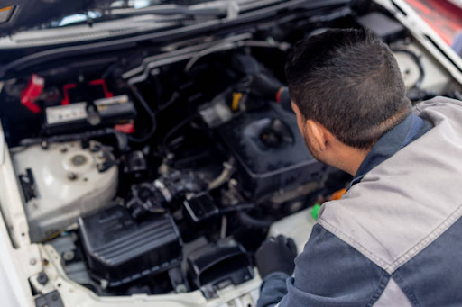 A man diligently repairs a car engine, emphasizing the importance of expert car repairs in Malaga for optimal results.
