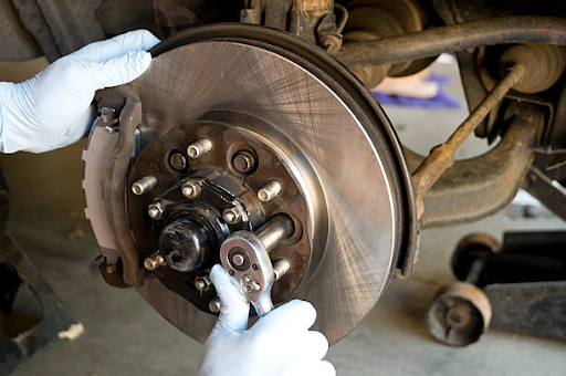 A person in white gloves is focused on brake repair work, illustrating the long-term advantages of regular brake servicing.