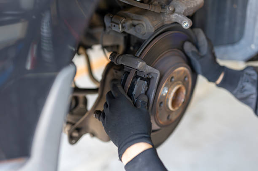 A person wearing black gloves is repairing a brake, illustrating the importance of understanding brake repair myths.