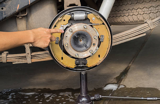 A person fine-tunes the brake system of a vehicle, emphasizing the impact of weather on brake repair needs.
