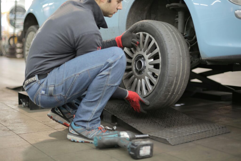 A man diligently repairs a car tire, showcasing expertise in tyres Malaga.