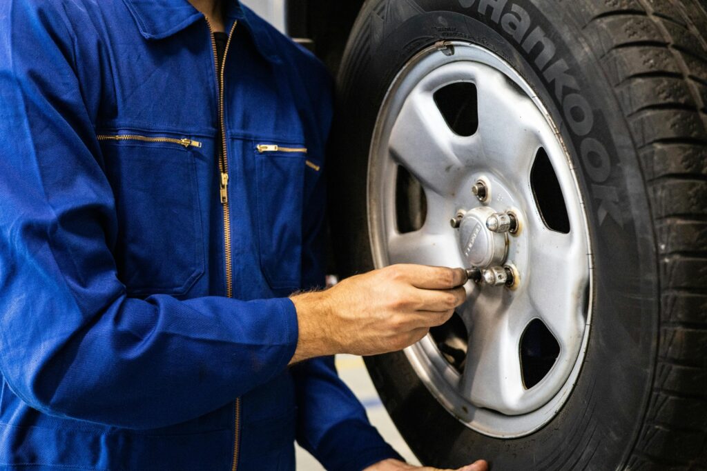 A man in blue overalls repairs a tire, showcasing expertise in tyres Malaga.