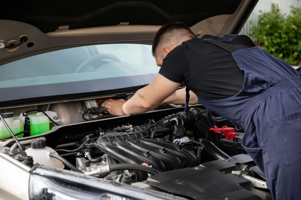 Man in overalls engaged in car repair work.